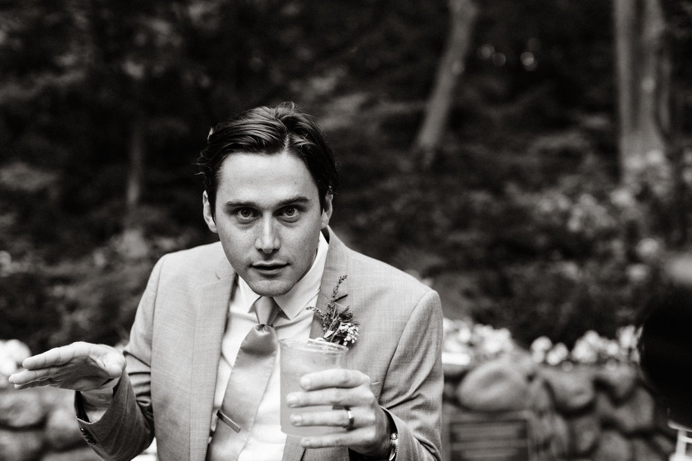 groom being playful while holding a drink with his wedding band