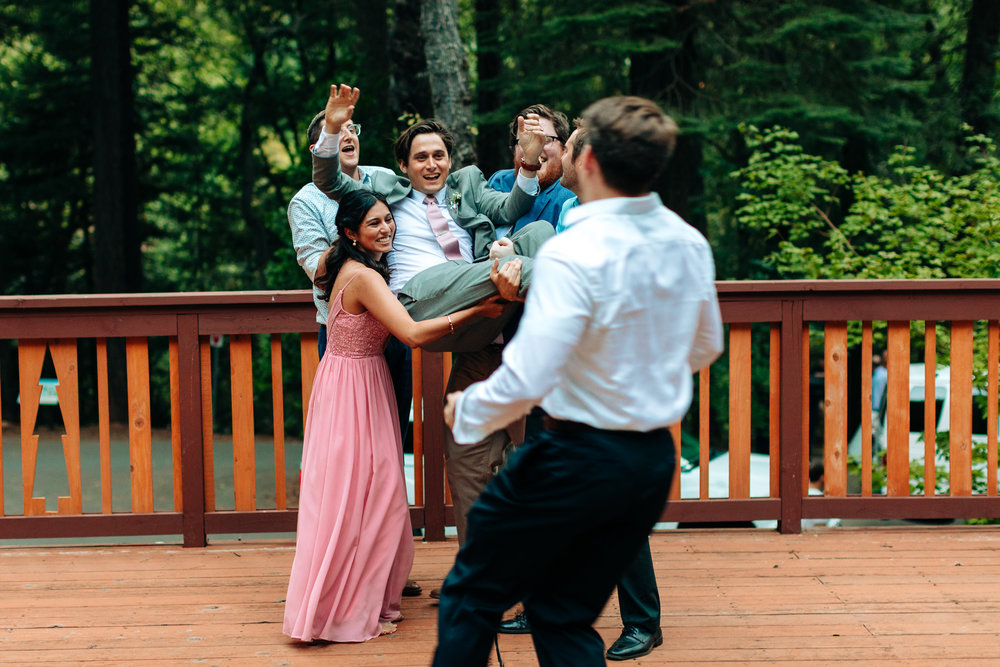 guests lifting happy groom during reception