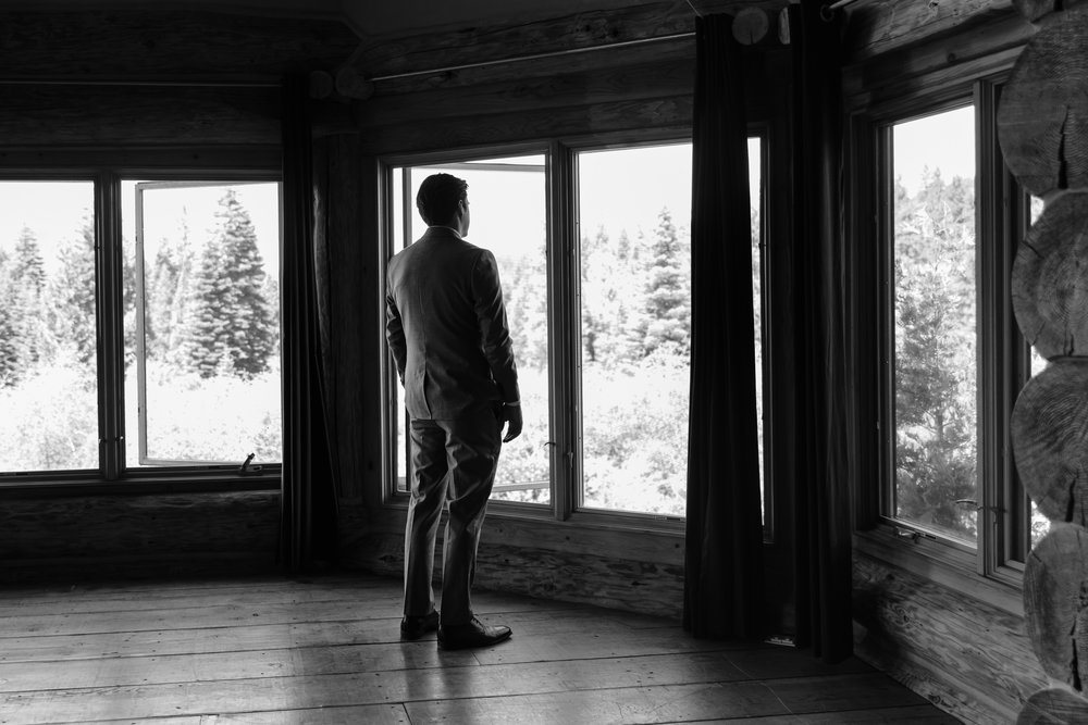 Groom looking out of natural light windows waiting for first look