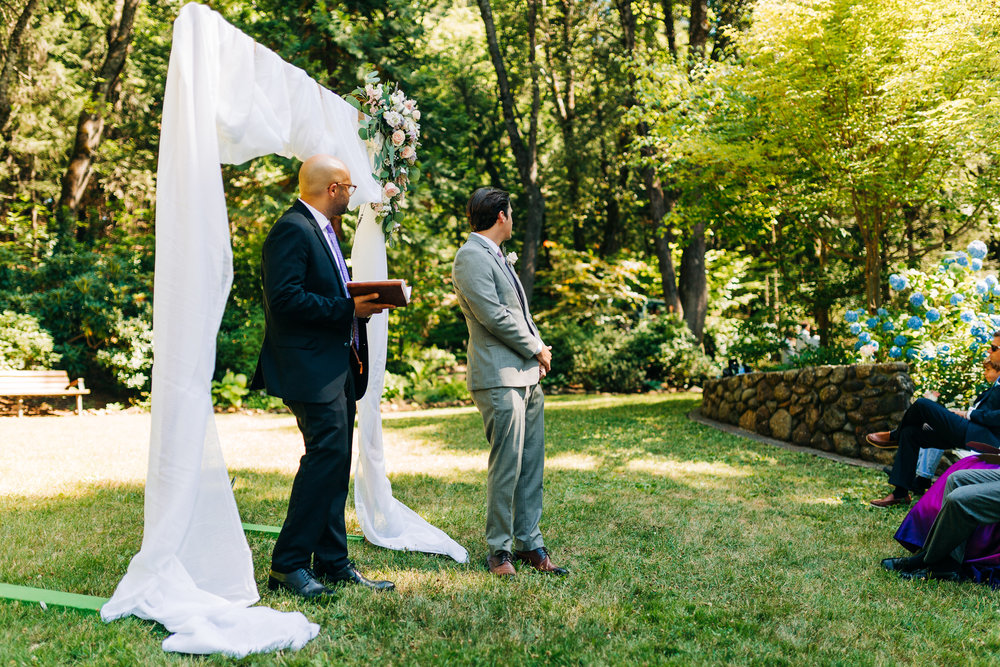 officiant and groom looking for bride when she arrives to her garden ceremony