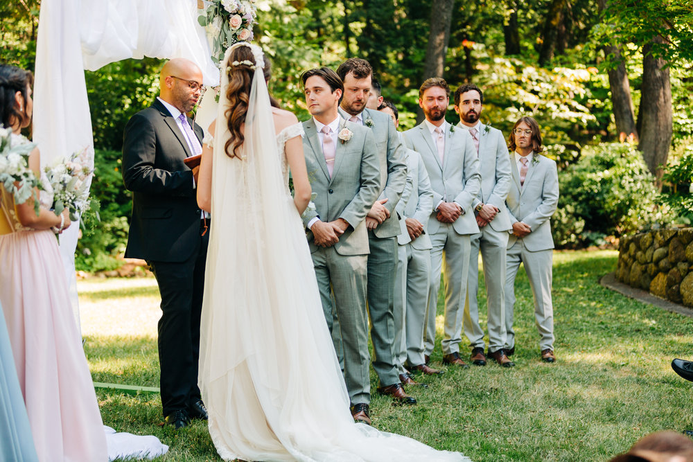 Groom with groomsmen in gray suits during a summer outdoor ceremony