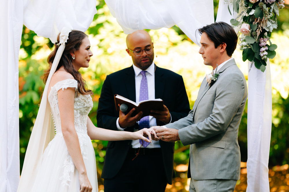 bride and groom saying vows and exchanging rings at a garden ceremony