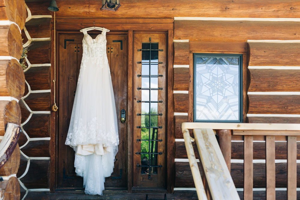 Chic Bohemian Bride wedding dress hanging on a door to a rustic lodge