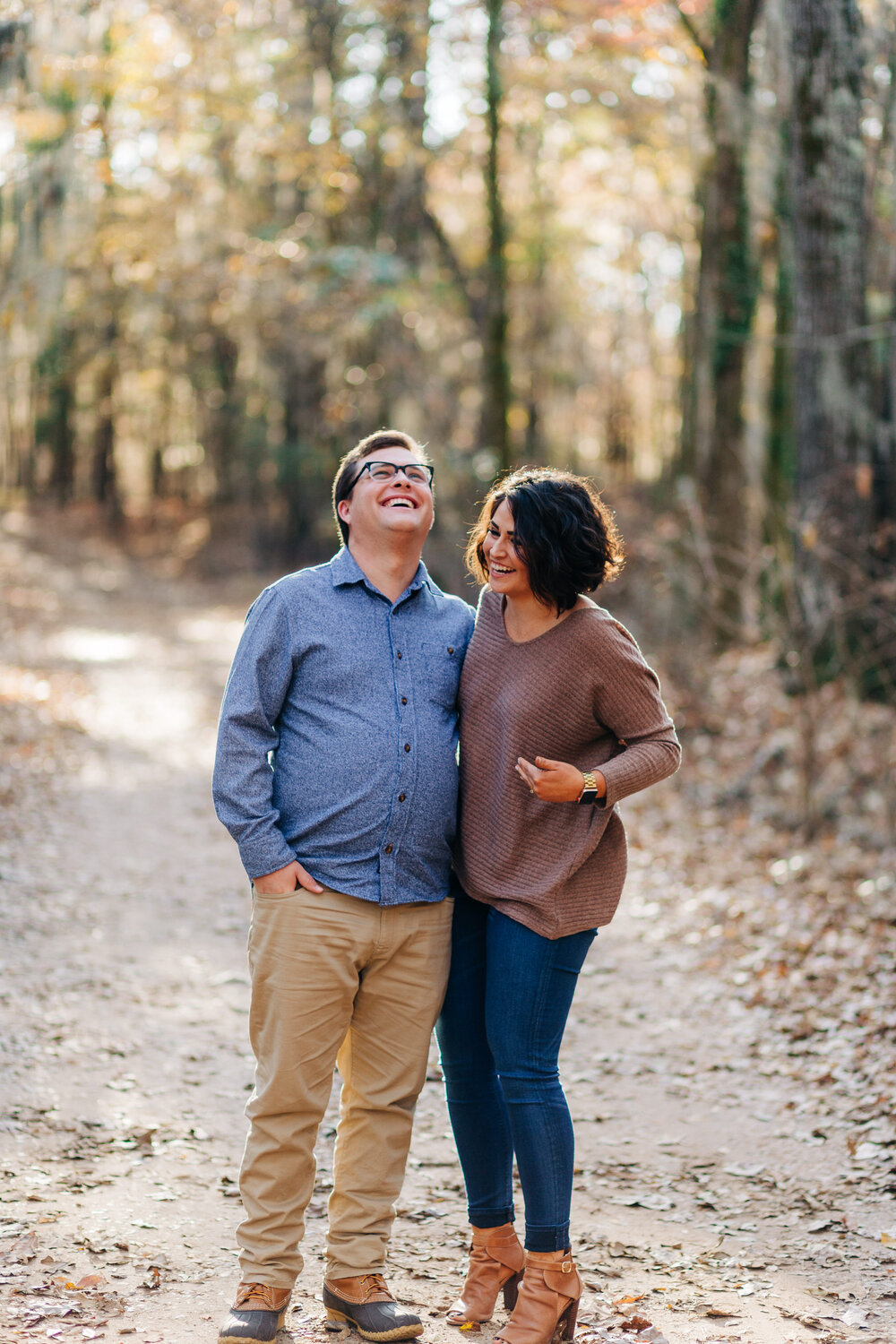 fun couple standing and laughing in a wooded driveway