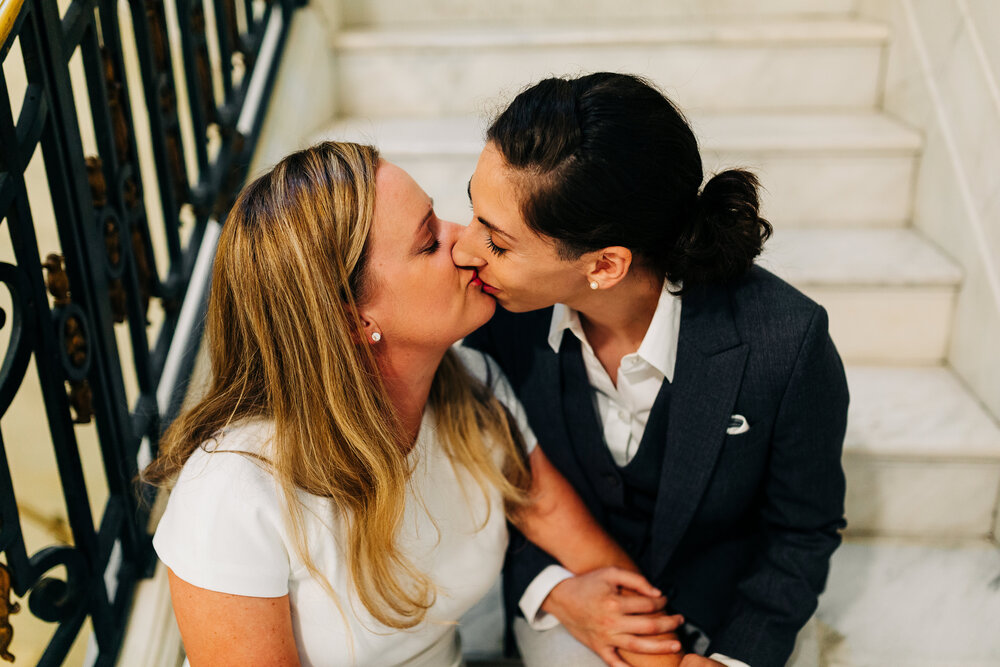 A close up romantic portrait of two marriers sharing a kiss on the marble stairs