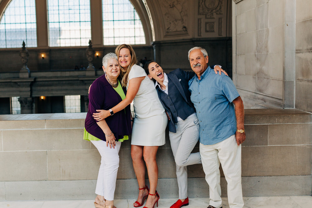 A playful portrait of two brides with parents on the fourth floor of city hall