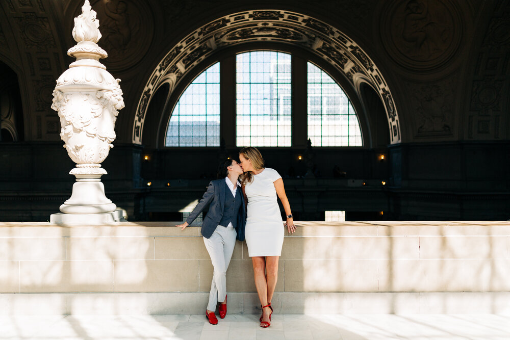 Two marriers share a kiss under the fourth floor ceilings at San Francisco City Hall