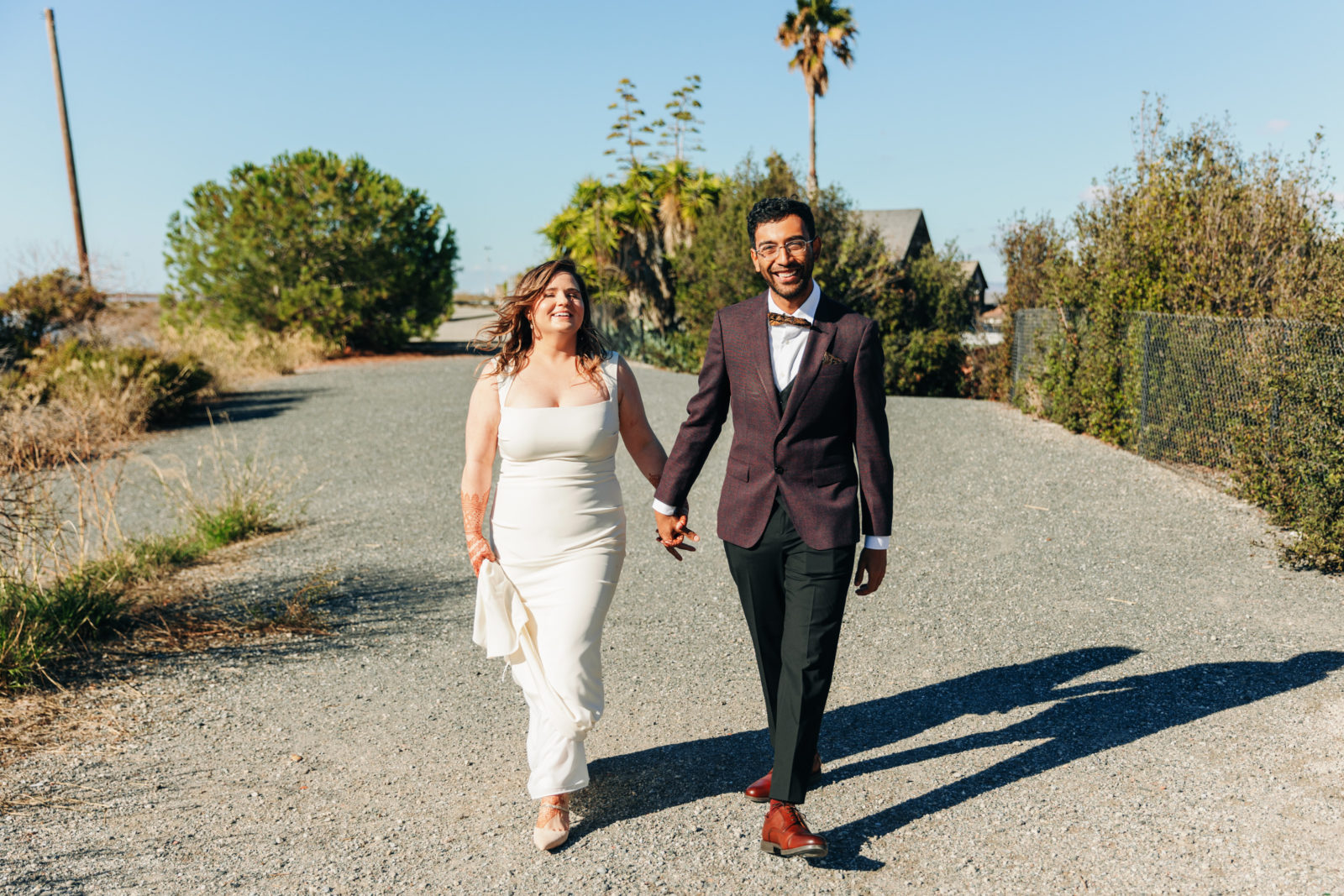 documentary style photo of a wedding couple smiling while walking along the water at a yacht club venue