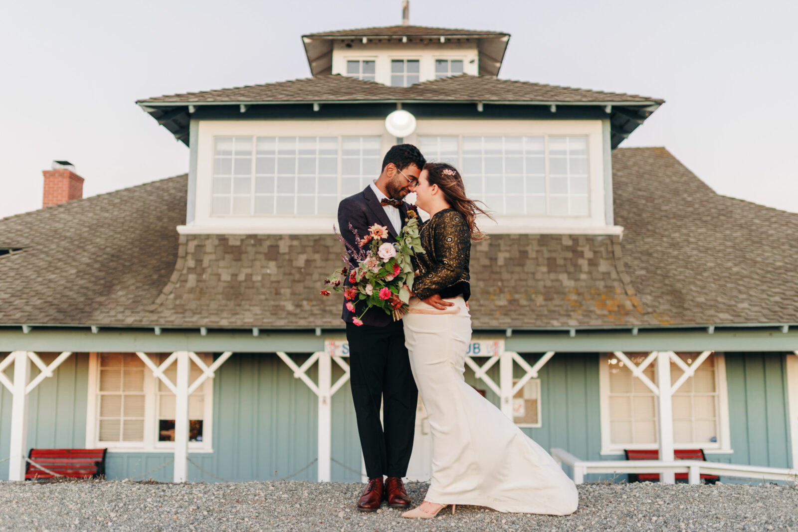 portrait of a wedding couple in front of a yacht club during a windy golden hour