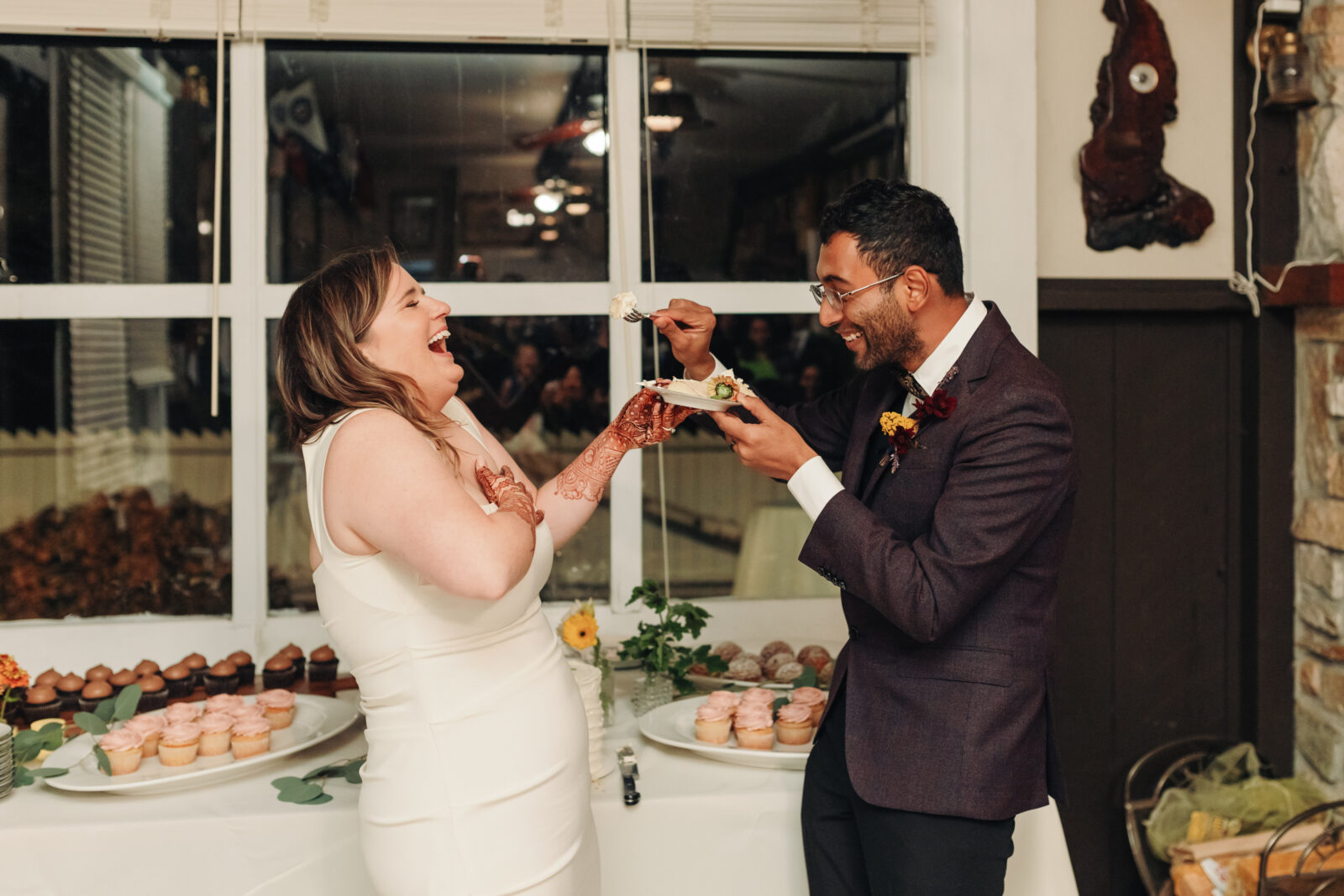 candid photo of a wedding couple laughing while cutting their cake at their yacht club reception