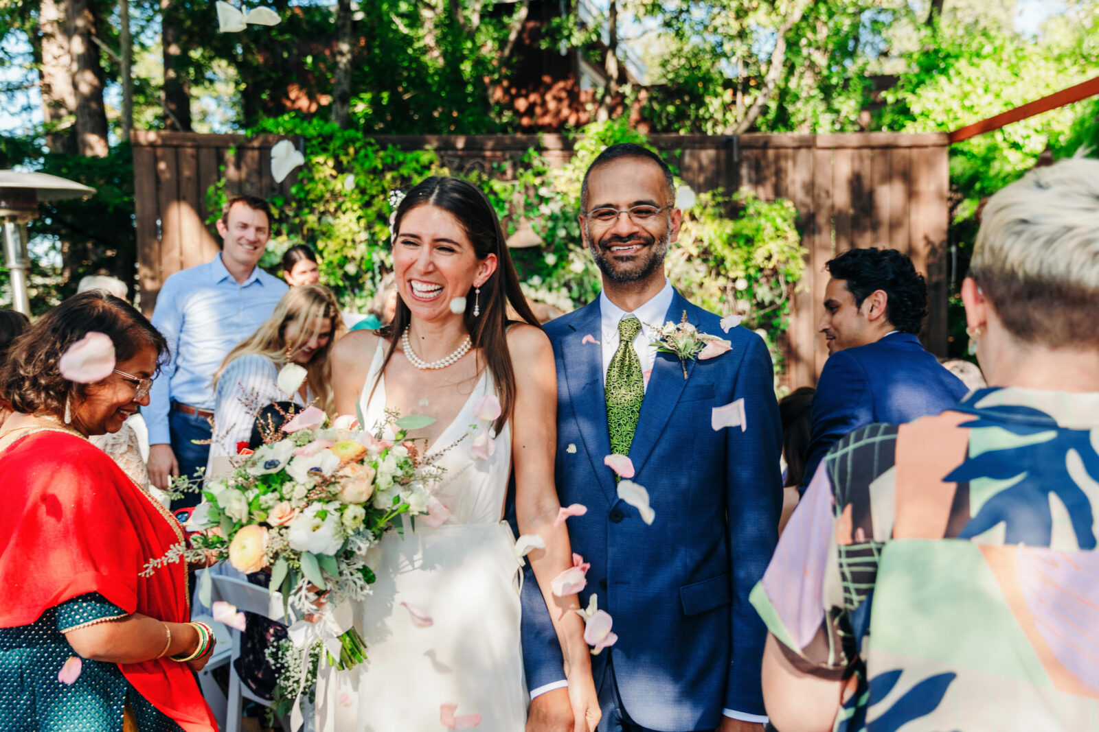 Newlyweds smile while walking through flower petals during their backyard wedding in Memphis
