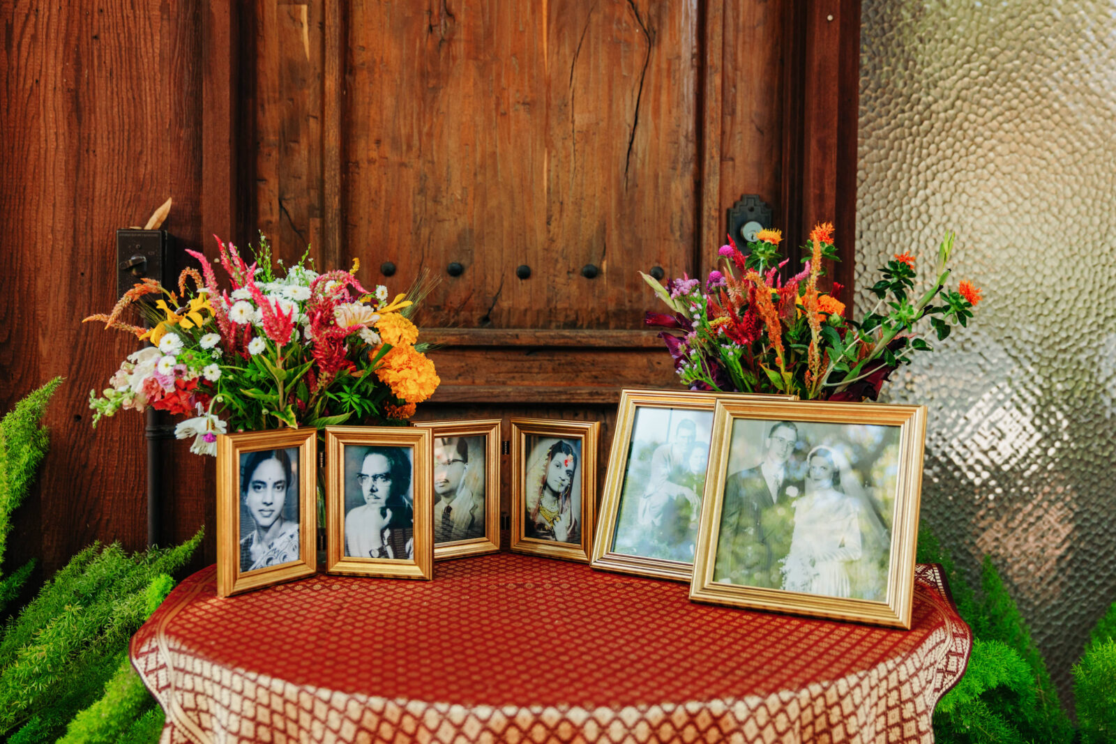 Vibrant flowers surround black and white wedding photos featuring the couple's parents