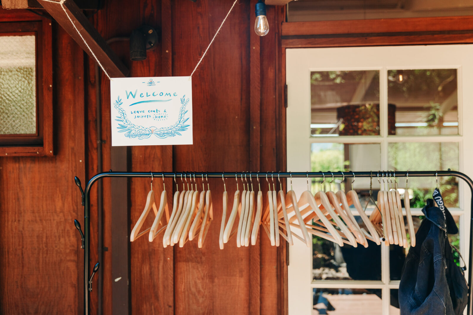 A handmade sign welcomes guests and asks them to leave their jackets on a coat rack