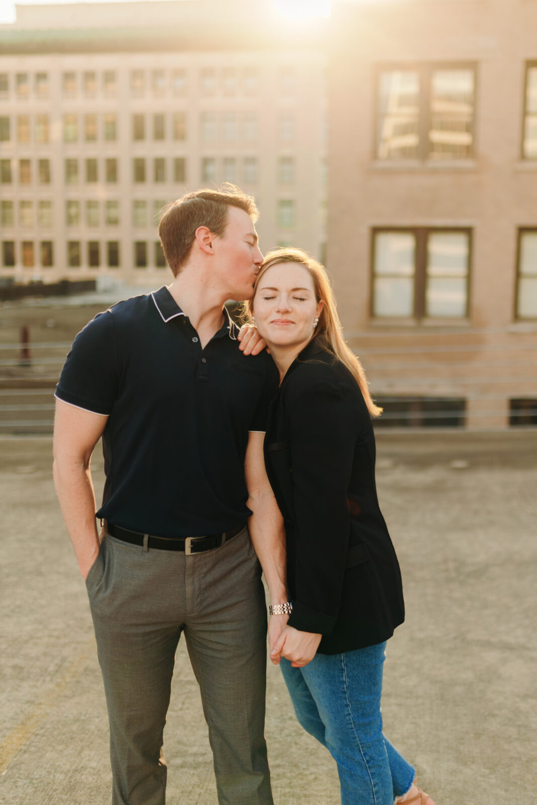 A couple smiling in golden hour backlight on a downtown rooftop during their engagement session in Memphis