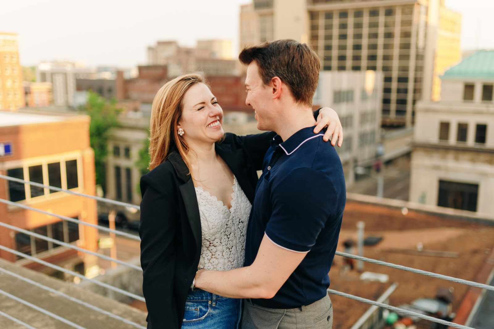 A couple smiling during golden on a rooftop overlooking downtown Memphis