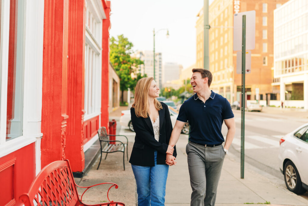 An engaged couple holding hands and walking along South Main Street in Memphis