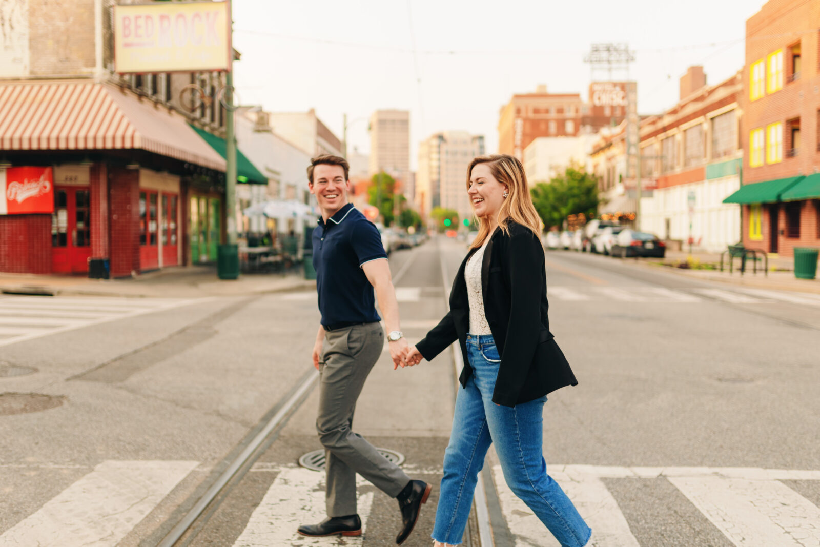 An engaged couple crossing South Main Street in Memphis during golden hour