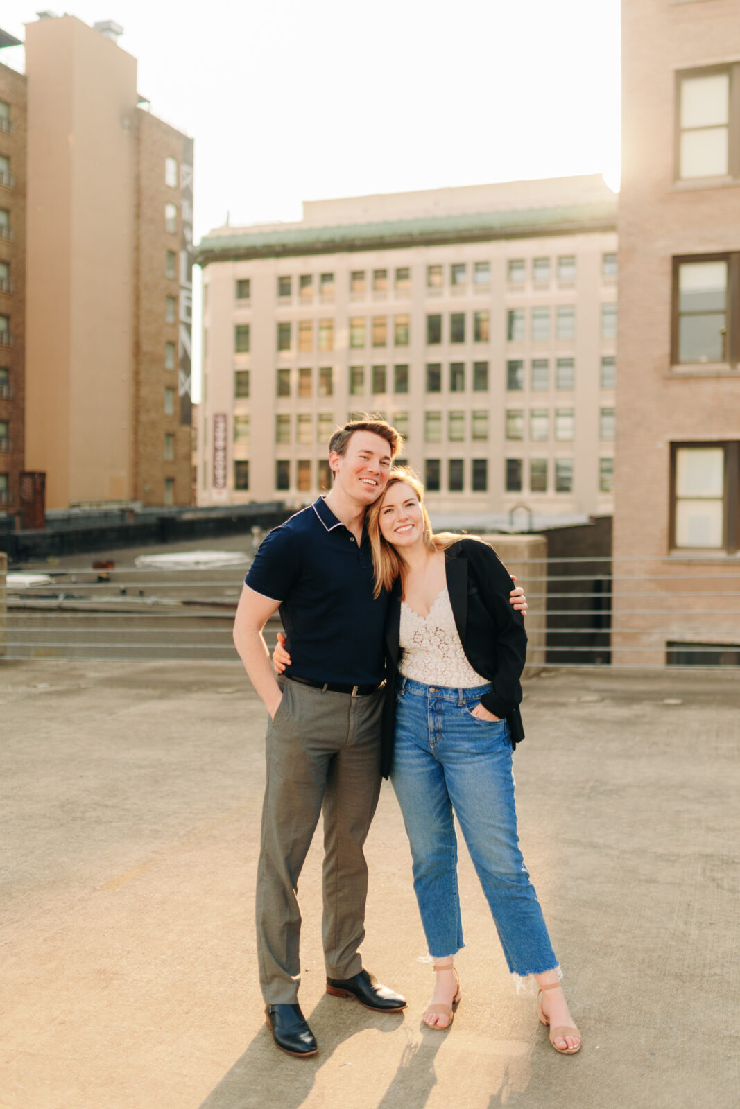 A couple smiling in golden hour backlight on a downtown rooftop during their engagement session in Memphis